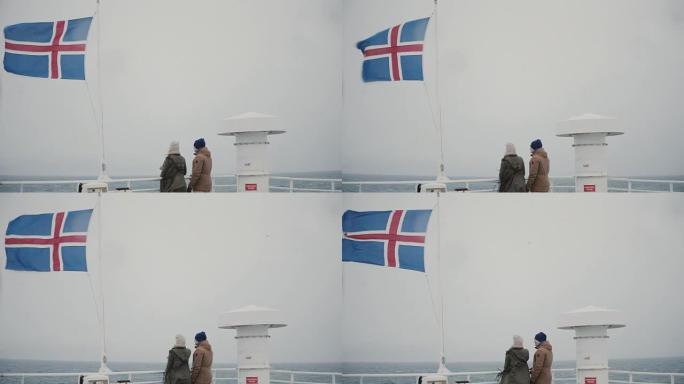 年轻夫妇站在船上，靠近冰岛国旗，看着大海，说话