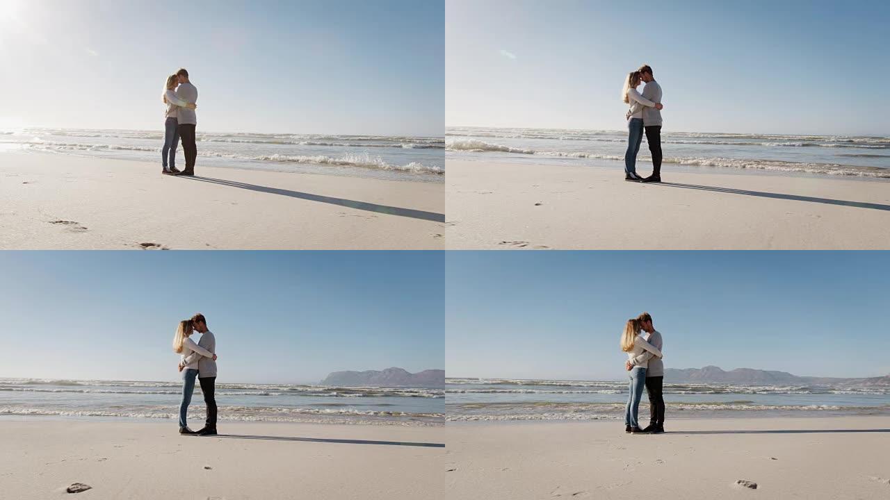 相爱的情侣一起拥抱在冬季海滩上