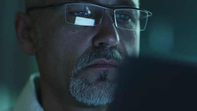 中年男性使用平板电脑的肖像，并在眼镜中反射屏幕