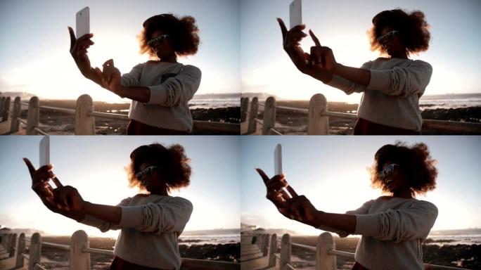 快乐的非洲裔美国潮人少女在海滩上用手机自拍