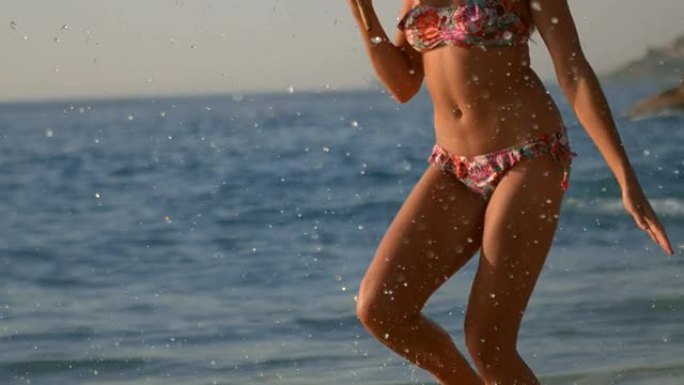快乐的女人打着伞在沙滩上奔跑