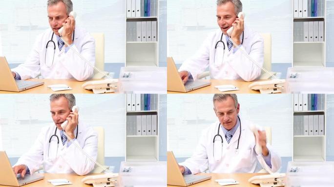 医生在电话上聊天，并在办公桌前使用笔记本电脑