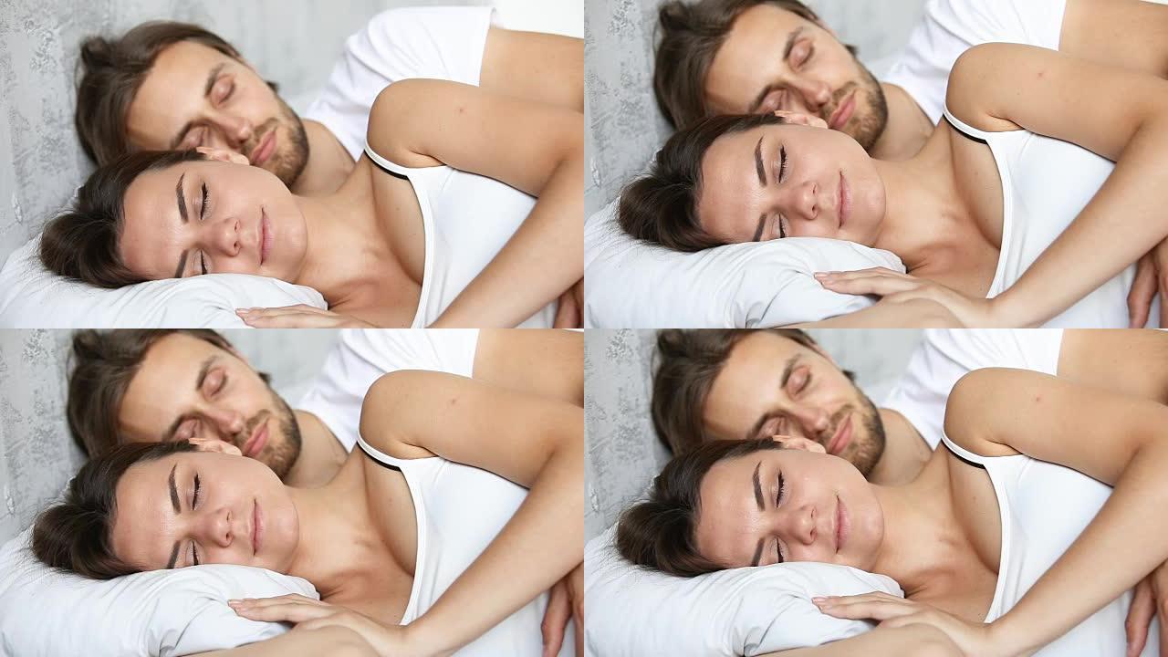 年轻夫妇睡在床上，躺在白色亚麻布上拥抱