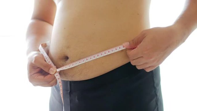 胖子用测量胶带测量腹部健康概念