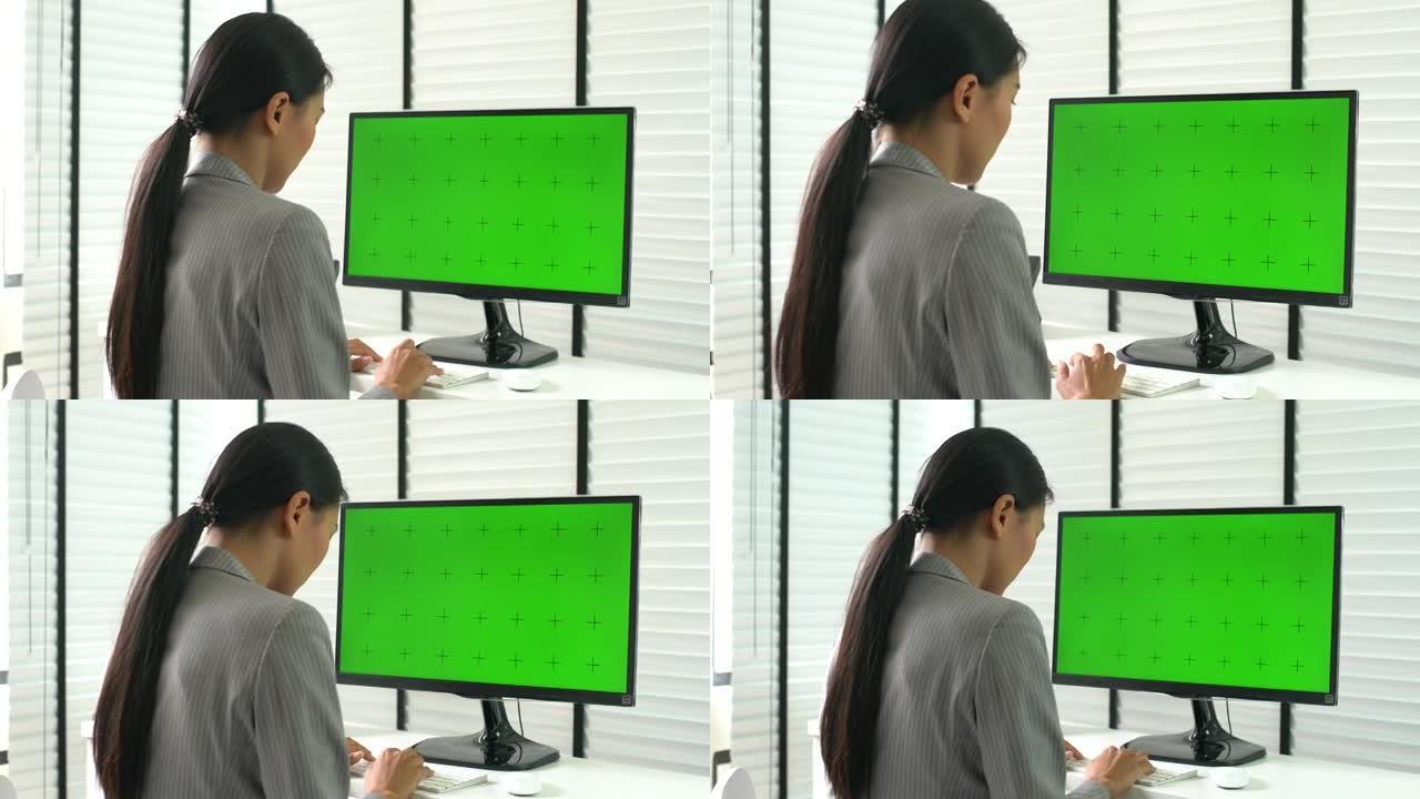 女人在办公室的绿屏上使用计算机