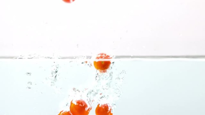 樱桃番茄落在白色背景上的水中