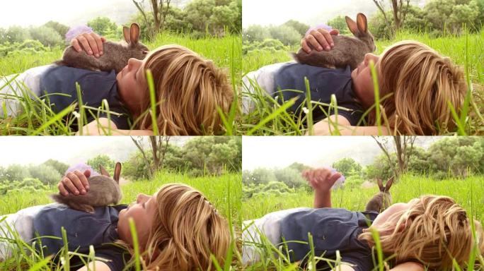 男孩喜欢他的小兔子躺在外面的草地上