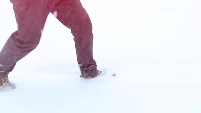穿着靴子走路的脚在慢动作的冬季景观上，在山上的冬季散步，度假旅游，飘雪