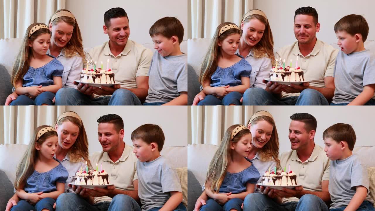 幸福的年轻家庭坐在沙发上庆祝生日