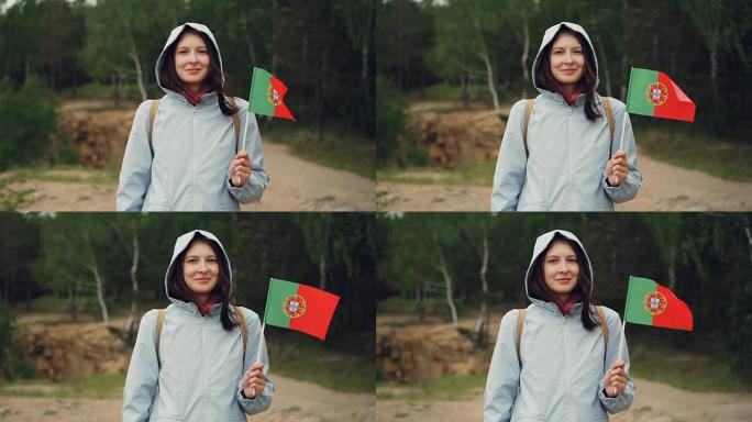 拿着葡萄牙国旗的迷人葡萄牙女孩的慢动作肖像，微笑着看着相机。公民，民族自豪感，春天的概念。