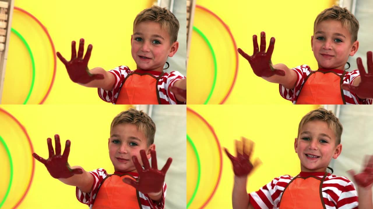 可爱的小男孩展示他凌乱的油漆覆盖的手