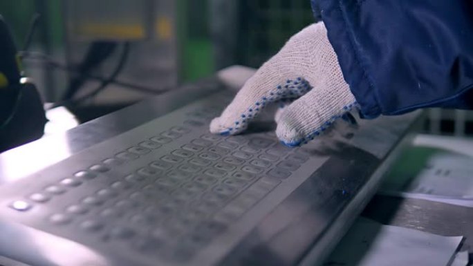 仓库工人用键盘戴手套的手。