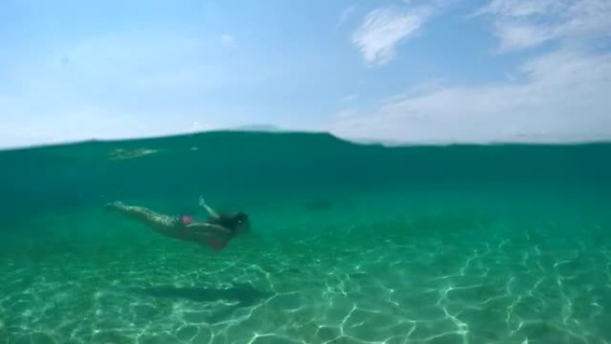 水下: 快乐的年轻女子在水下游泳并浮出水面