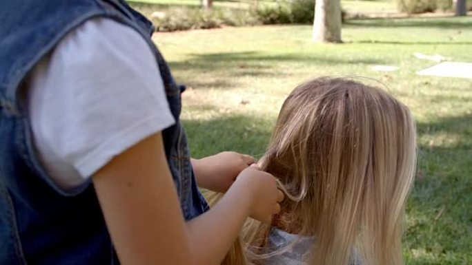 小女儿在公园编织母亲的头发