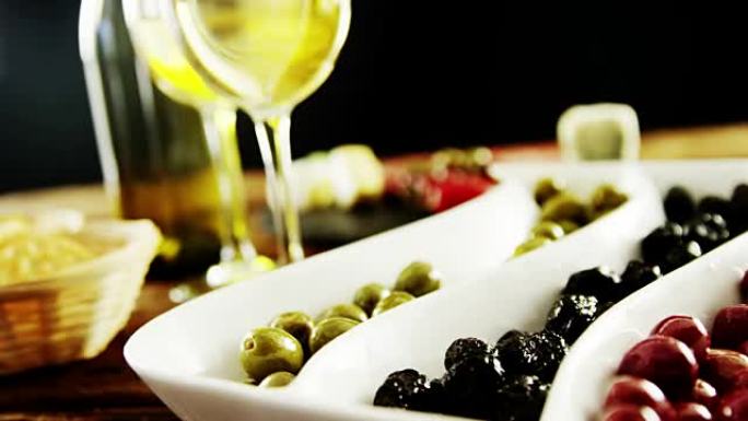 两杯葡萄酒和一个装有浆果水果和橄榄的托盘