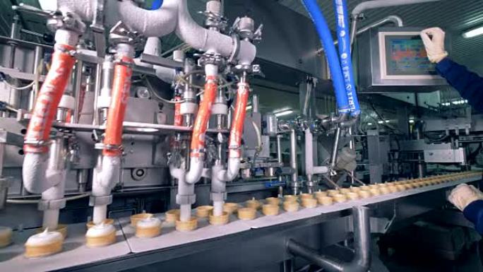 工人在工厂输送机上控制冰淇淋生产过程。