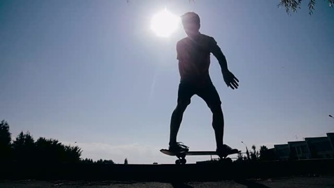 滑冰运动员骑在滑板上的史诗剪影。背景上的日落天空。慢动作，稳定拍摄