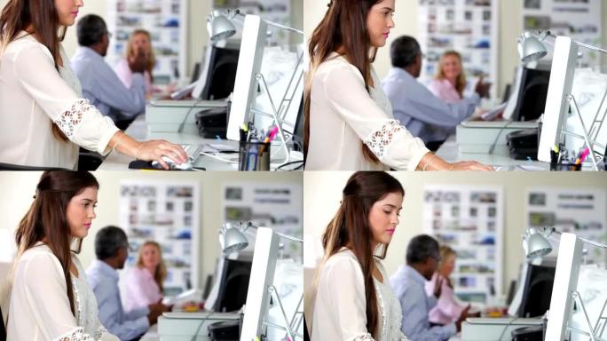 女人在忙碌的创意中使用办公桌上的电脑