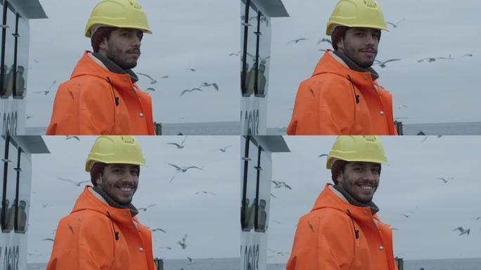 穿着鲜艳防护外套的肖像在商业渔船上微笑着渔夫。