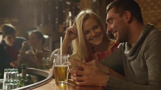 男人和女人在使用智能手机并在酒吧里玩得开心时会笑。