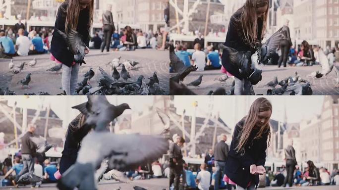 高加索小女孩在外面喂鸟。慢动作。快乐的女孩子在拥挤的阳光城广场上喂鸽子