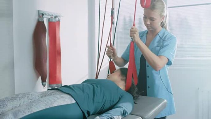 物理治疗师协助女性创伤患者，在特殊的悬吊绳系统上进行康复理疗。缓解颈部、背部、头痛。现代诊所使用最先