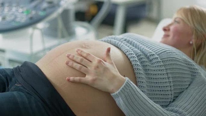 在医院里，聚焦镜头对准躺在床上的孕妇，抚摸她的腹部，感觉婴儿被踢。