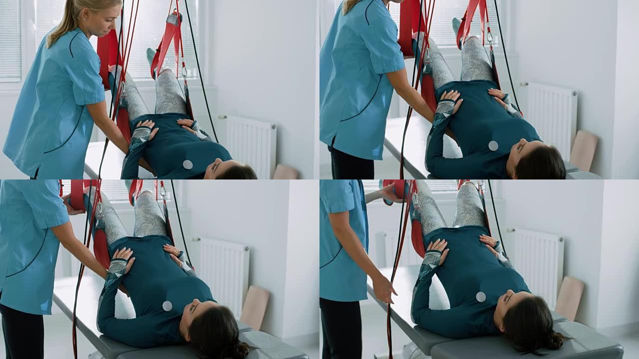 物理治疗师协助女性创伤患者，在特殊的悬吊绳系统上进行康复理疗。缓解背痛。现代诊所使用最先进的康复程序