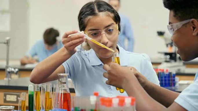 女STEM学校学生与男实验室伙伴进行化学实验