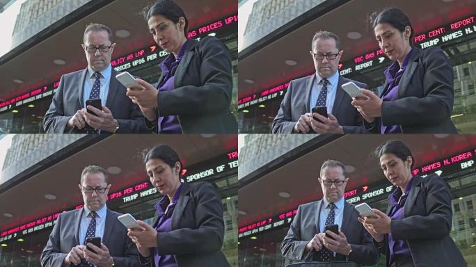 两名商务人士在街上手机查看新闻的实时视频