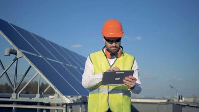 一名工人使用平板电脑，计算屋顶上的太阳能电池板。4K。