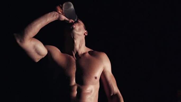 健康的肌肉男子饮用水或能量饮料