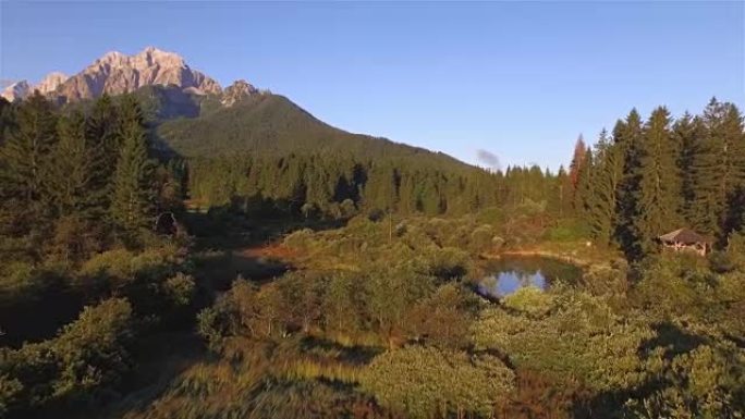 空中: 在阳光明媚的早晨，飞越美丽的秋天草地，越过湖面朝落基山脉飞行