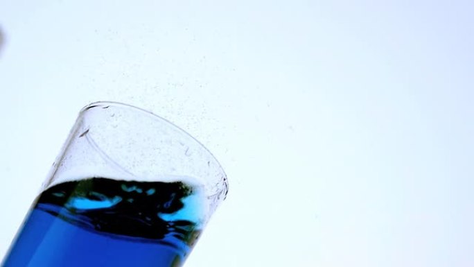 冰落下，错过了蓝色液体的玻璃