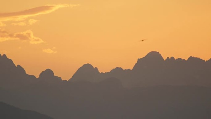 黄昏时，鸟影飞越欧洲阿尔卑斯山的山峰