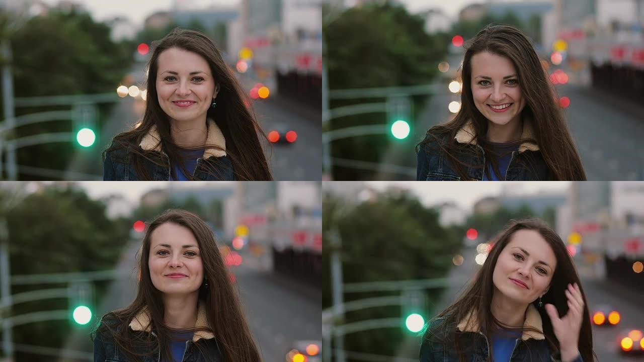风吹长发美丽的年轻女性。微笑的女孩晚上站在桥上，看着相机。全高清
