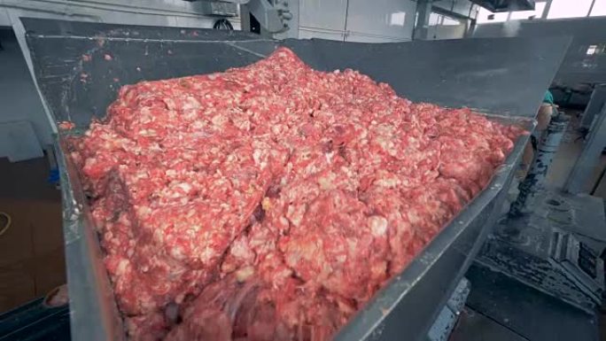 一堆肉被从一个小容器丢弃到一个更大的容器中，在那里搅拌
