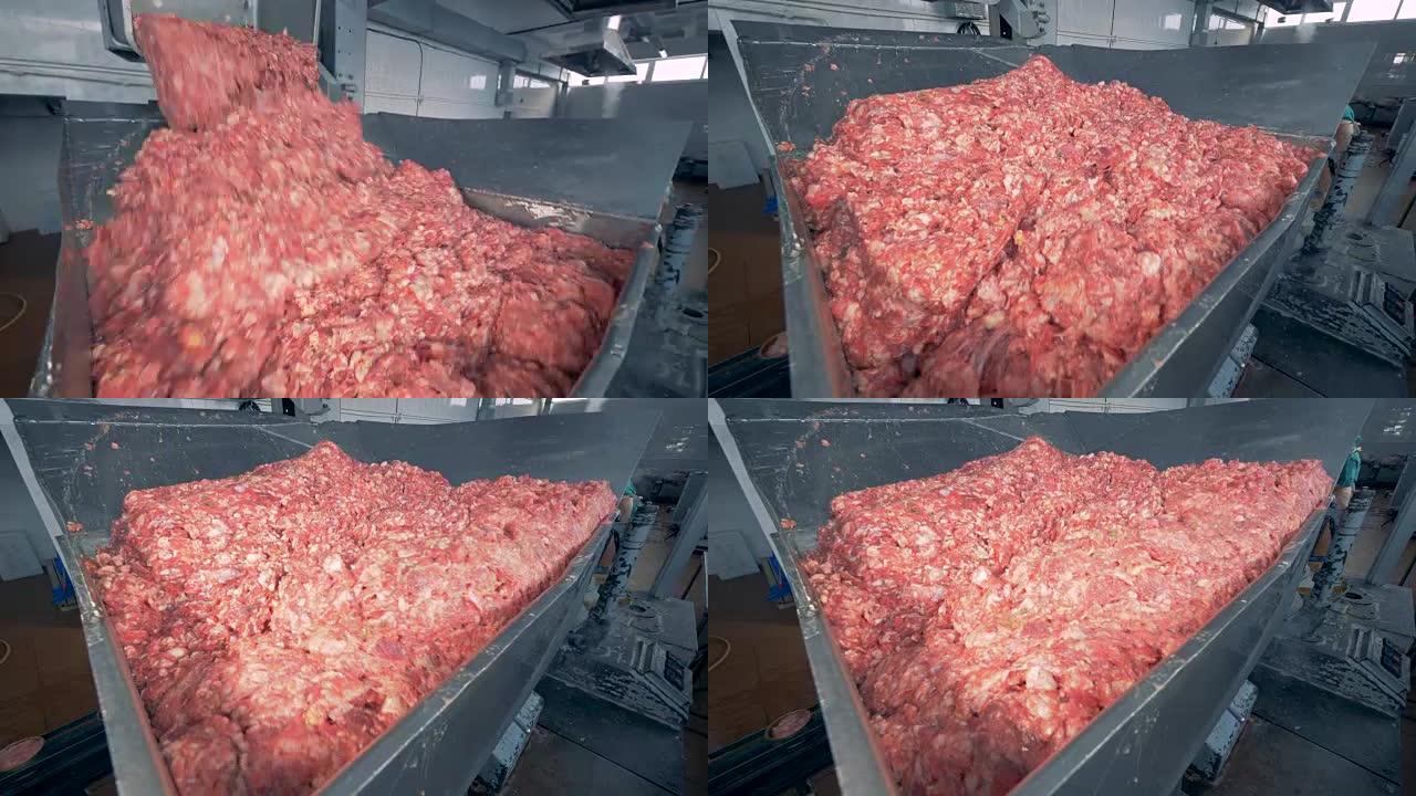 一堆肉被从一个小容器丢弃到一个更大的容器中，在那里搅拌