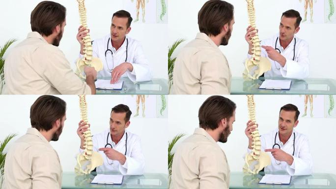 医生向病人展示骨骼脊柱模型