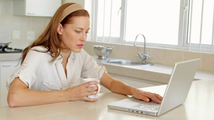 美丽的黑发女人喝咖啡和使用笔记本电脑