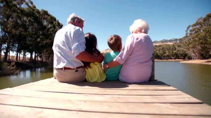 祖父母和孙子坐在湖边码头上