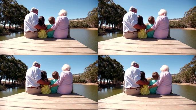 祖父母和孙子坐在湖边码头上