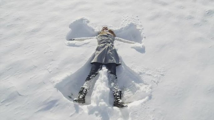 慢动作: 微笑的年轻女子制作雪天使