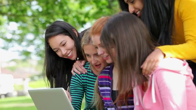 女学生在外面一起看着笔记本电脑笑