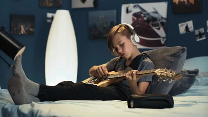 戴着耳机的男孩用吉他学习歌曲