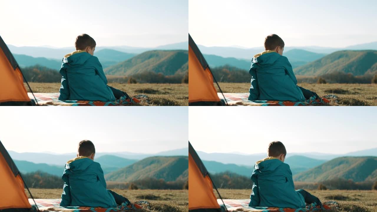 坐在山顶帐篷前的男孩