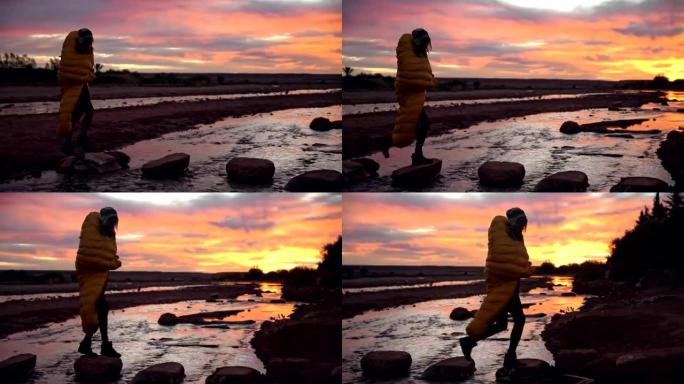 Beautiful sunset. Woman crossing river
