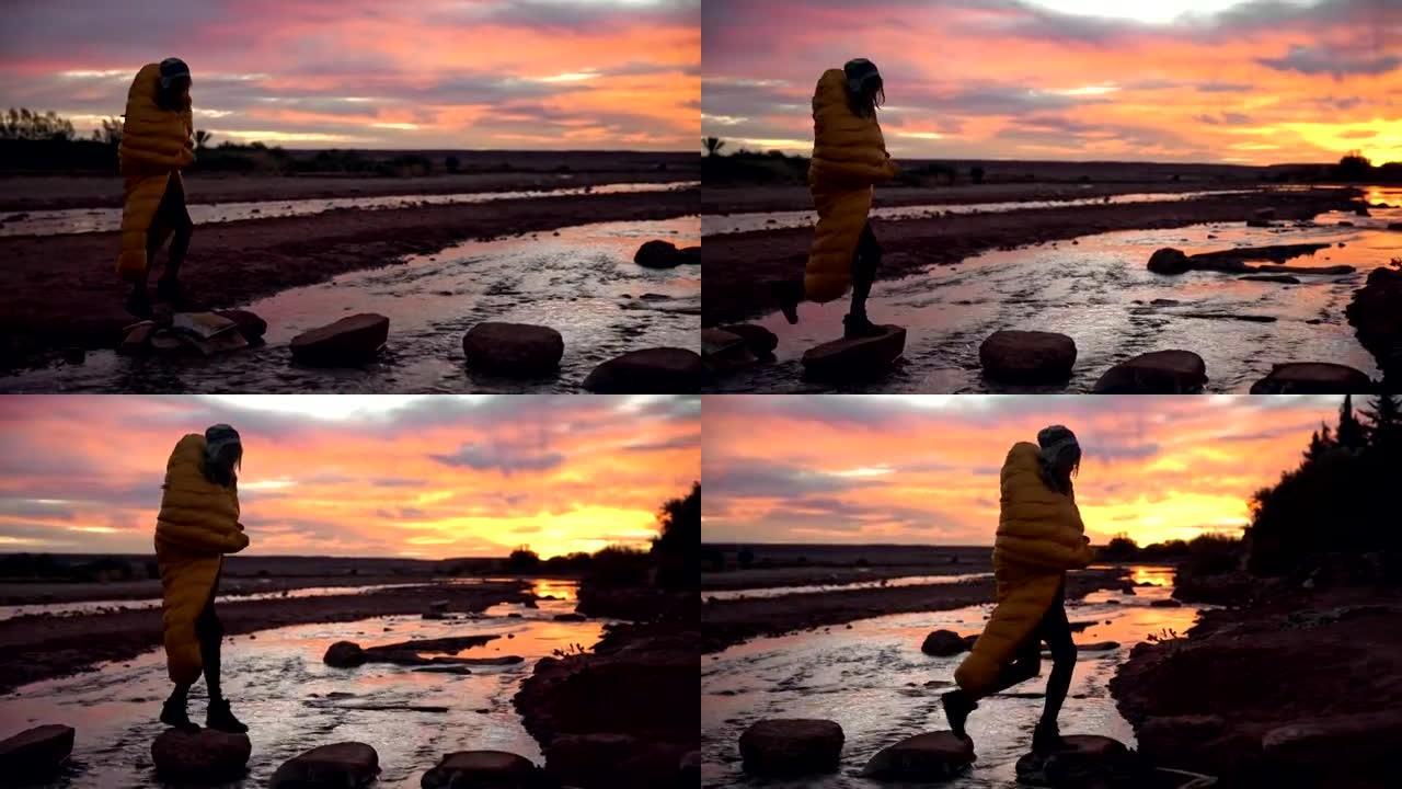 Beautiful sunset. Woman crossing river