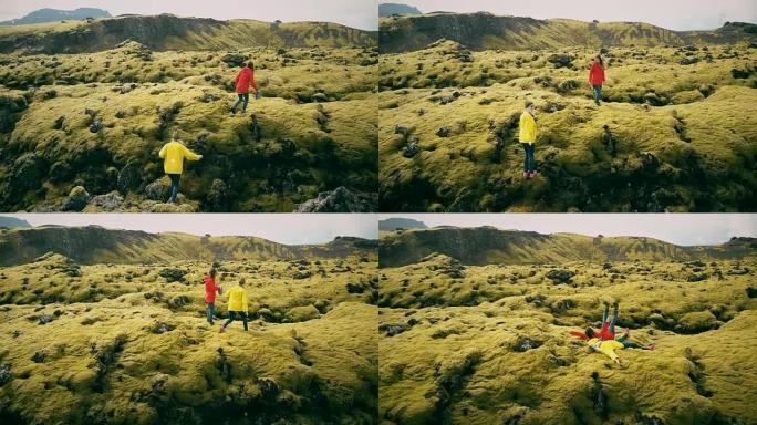 在冰岛的熔岩场上徒步旅行的两个女人的鸟瞰图。游客摔倒在柔软的苔藓上