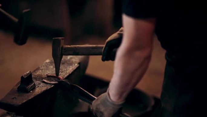 两个男人用锤子一起做马蹄铁。铁匠在工作场所的围裙中使用热金属